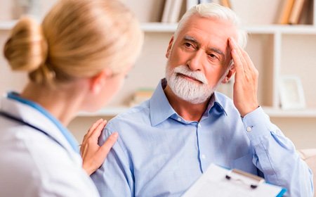 Пожилой мужчина держит руку у лица